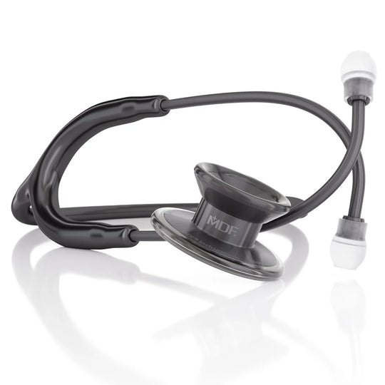 A black medical stethoscope with a metallic silver chestpiece and white ear tips, displayed on a clean white reflective surface. The chestpiece features the brand name 'MDF' printed on it.